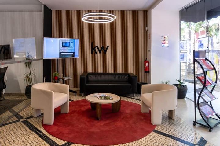 Sala de espera do piso 0 da KW Area em Lisboa, com poltronas claras e tapete encarnado